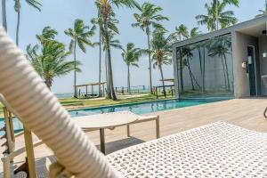 - une vue sur la piscine depuis une maison avec des palmiers dans l'établissement Anaya - Villas de Luxo, à Passo de Camarajibe