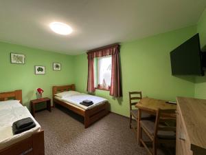 Zimmer mit 2 Betten, einem Tisch und einem Schreibtisch in der Unterkunft Ubytování Smrk in Nové Město pod Smrkem
