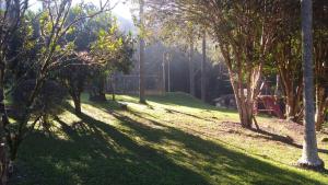 a park with trees and a playground in the distance at Casa de campo agradável com piscina, parquinho, lago, riacho, quadra, sinuca e mais! in Juquitiba