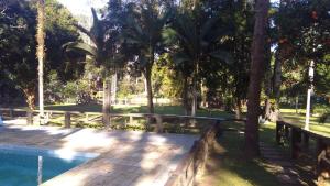 a wooden deck next to a swimming pool with palm trees at Casa de campo agradável com piscina, parquinho, lago, riacho, quadra, sinuca e mais! in Juquitiba