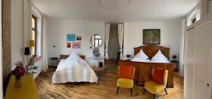 a bedroom with a bed and two chairs and a mirror at Künstlerzimmer im Kulturhaus Häselburg in Gera