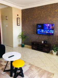 a living room with a table and a tv on a wall at Maritah Homes in Kampala