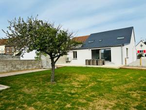 a white house with a tree in the yard at Cap à la mer in Sangatte