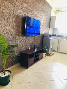 a living room with a tv on a stone wall at Maritah Homes in Kampala