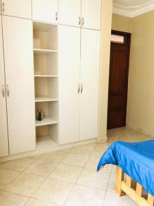 a bedroom with white cabinets and a blue bed at Maritah Homes in Kampala