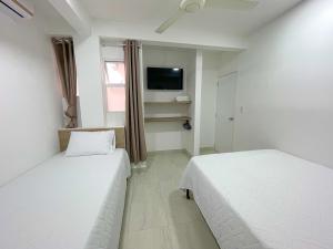 um quarto com duas camas e uma televisão na parede em Casa Victoria em Montería