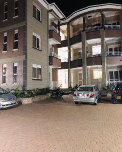two cars parked in a parking lot in front of a building at Maritah Homes in Kampala
