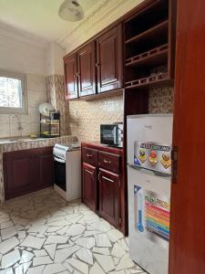 a kitchen with wooden cabinets and a white refrigerator at Lekker Estate in Yaoundé