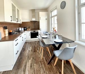 cocina con armarios blancos, mesa y sillas en BackHome - Fantastische Schlosslage, SmartTV, Netflix, 70qm, 24h Checkin - Apartment 2 en Ludwigsburg