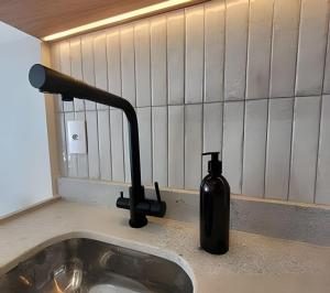 a black bottle sitting on a counter next to a sink at Uwin Brooklin in Sao Paulo