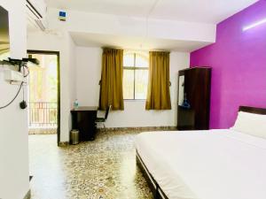 a bedroom with a bed and a purple wall at Budget Private Ac Room with Kitchen Near Osho Garden in Pune