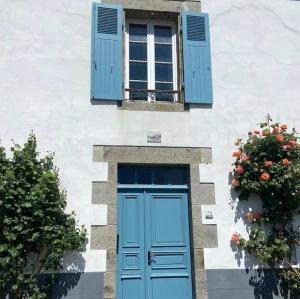 un edificio con una puerta azul, una ventana y flores en Appart les Mouettes-face à la mer et au sentier des douaniers, en Planguenoual
