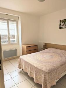 a white bedroom with a bed and a window at Appart les Mouettes-face à la mer et au sentier des douaniers in Planguenoual