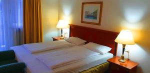 uma cama num quarto de hotel com duas lâmpadas em Alpenhotel Gastager em Inzell