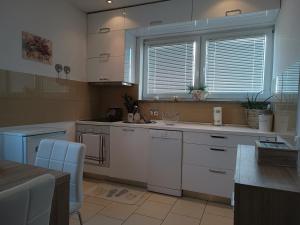 a kitchen with white cabinets and a large window at Apartment Luka in Fažana