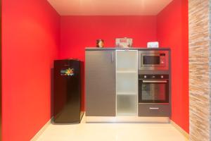 a red kitchen with a refrigerator and a microwave at casa picota in Oia +20 photos