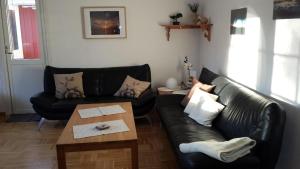 ein Wohnzimmer mit einem schwarzen Ledersofa und einem Tisch in der Unterkunft Geräumiges Ferienhaus mit Außensauna, in der Nähe vom Storforsen, Schwedens größten Stromschnellen in Vidsel