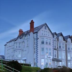 un gran edificio blanco con un cartel. en Caerwylan Hotel, en Criccieth