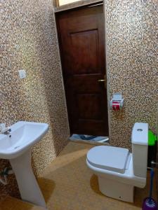 baño con aseo, lavabo y puerta en Palm Grove lodge, en Busua