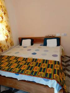 a bedroom with a bed with a colorful comforter at Palm Grove lodge,Busua in Busua +9 photos
