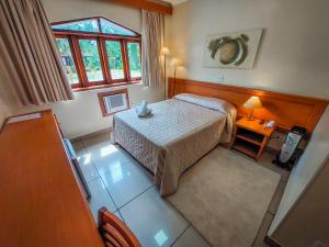 um pequeno quarto com uma cama e uma janela em Hotel Nacional Inn Campos do Jordão em Campos do Jordão