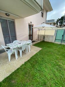 a patio with a table and an umbrella on the grass at Appartamento a 100m dal mare in Grottammare
