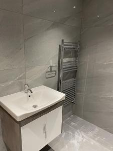 uma casa de banho com um lavatório branco e um chuveiro em Impeccable Holiday House in London Sleeps four em Londres