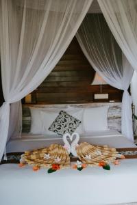 a bed with white curtains and food on it at Dini D'Nusa Lembongan in Nusa Lembongan