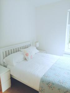 ein Bett mit weißer Bettwäsche und Kissen in einem Schlafzimmer in der Unterkunft Carolina Cottage in Buncrana