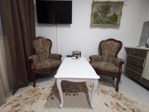 sala de estar con 2 sillas y mesa blanca en In Apartments AirPort en Mitrovići