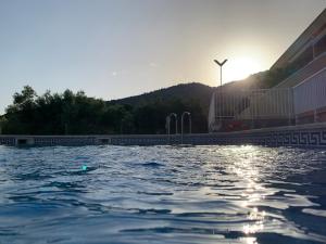 una piscina con el sol reflejándose en el agua en Apartamento con piscina privada y vistas al mar, en Alcanar