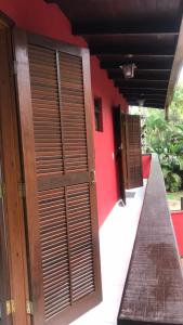 a building with wooden doors and a red wall at Suites Cambury in São Sebastião