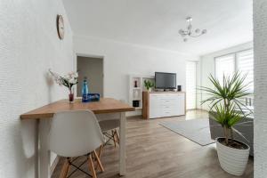 a living room with a wooden table and white chairs at Apartament Gold - 2 osobne sypialnie z balkonem - SpaceApart in Jelenia Góra