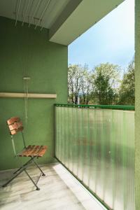 een stoel op een balkon met een groene muur bij Apartament Gold - 2 osobne sypialnie z balkonem - SpaceApart in Jelenia Góra