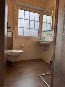 a bathroom with a toilet and a sink and a window at Ferienwohnung Norddeich: Gemütliche Rückzugsoase für 2-4 Personen in Norden