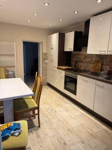 a kitchen with white cabinets and a table and chairs at Haus mit Garten , 5 Zimmer , Grillhaus, Whirlpool in Neumünster