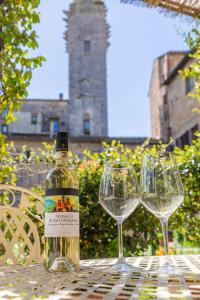 サン・ジミニャーノにあるFabio Apartments San Gimignanoのワイン1本とワイングラス2杯(テーブル上)