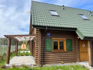 a small wooden house with a green roof at Dzikie Gąski in Gąski