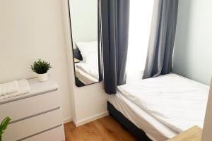 - une petite chambre avec un lit et un miroir dans l'établissement Großzügiges City-Apartment in Mönchengladbach, à Mönchengladbach