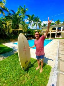 Un homme debout à côté d'une planche de surf avec sa main dans l'air dans l'établissement Casaola Mizata, à Santa María Mizata