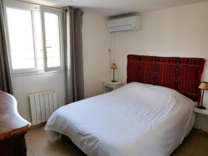 a bedroom with a bed with a red headboard and two windows at Right by the Sea • Les Embruns in Martigues