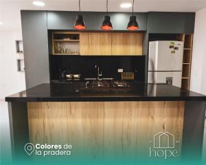uma cozinha com um balcão preto e um frigorífico em Colores de la pradera by Hope em Guatapé