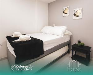 a bedroom with a bed with white sheets and pillows at Colores de la pradera by Hope in Guatapé +2 photos