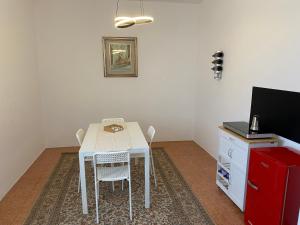 Appartamento 7 Laghi في Lomnago: غرفة طعام مع طاولة بيضاء وخزانة حمراء