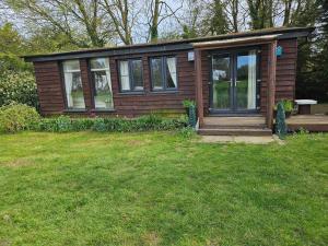 a small house with a porch and a grass yard at Remarkable 1-Bed Cabin in Dunmow in Great Dunmow