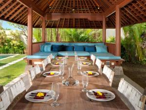 a long wooden table with wine glasses on it at Villa Joss Seminyak by Nagisa Bali in Seminyak