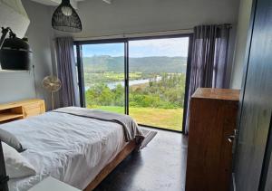 a bedroom with a bed and a large window at Cloud 9 Estate - Chalet in Knysna