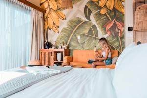 Eine Frau, die auf einer orangenen Couch im Schlafzimmer sitzt. in der Unterkunft Bambuda Bocas Town in Bocas del Toro