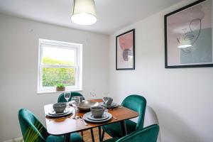 une salle à manger avec une table et des chaises vertes dans l'établissement Serene 3BR Cottage Escape: Parking, Kitchen, Wi-Fi, à Northampton