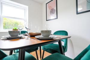 a dining room with a table and green chairs at Serene 3BR Cottage Escape: Parking, Kitchen, Wi-Fi in Northampton